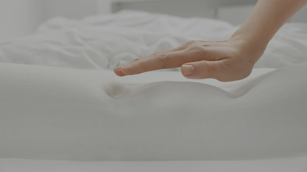 Hand pushing down on a foam mattress