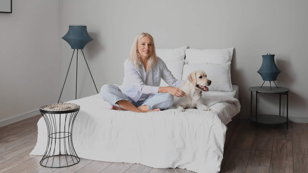 Woman sitting on bed with her dog