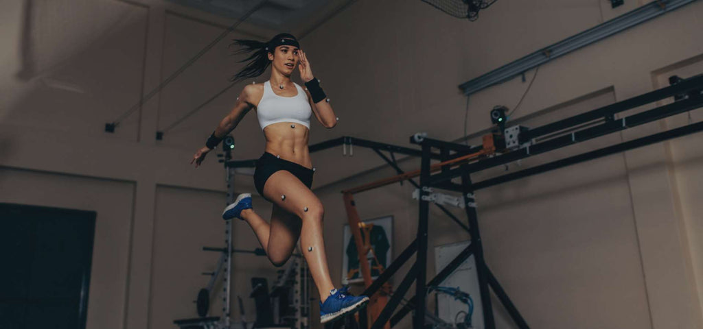 Woman sprinting while being attached to trackers to track her speed and performance