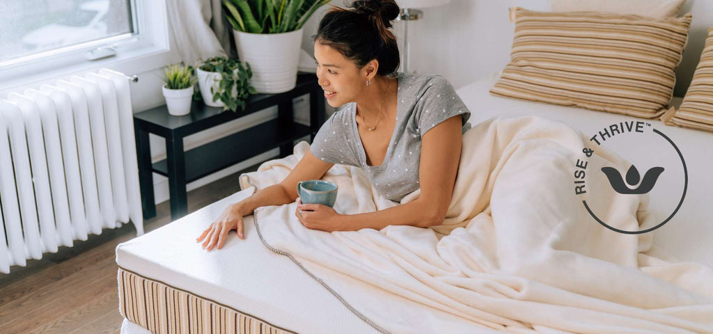 Woman on Essentia organic mattress with the Essentia Rise and Thrive logo