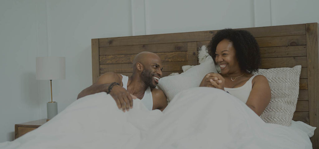 Husband and wife waking up smiling.