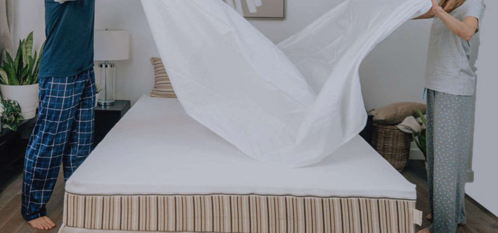 Man and woman putting a sheet on an Essentia mattress