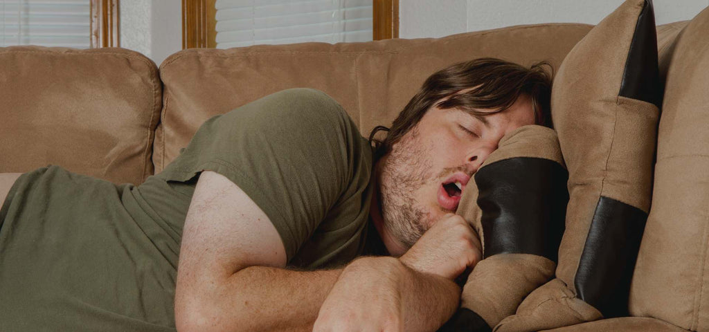 Man napping on a brown couch with his mouth open