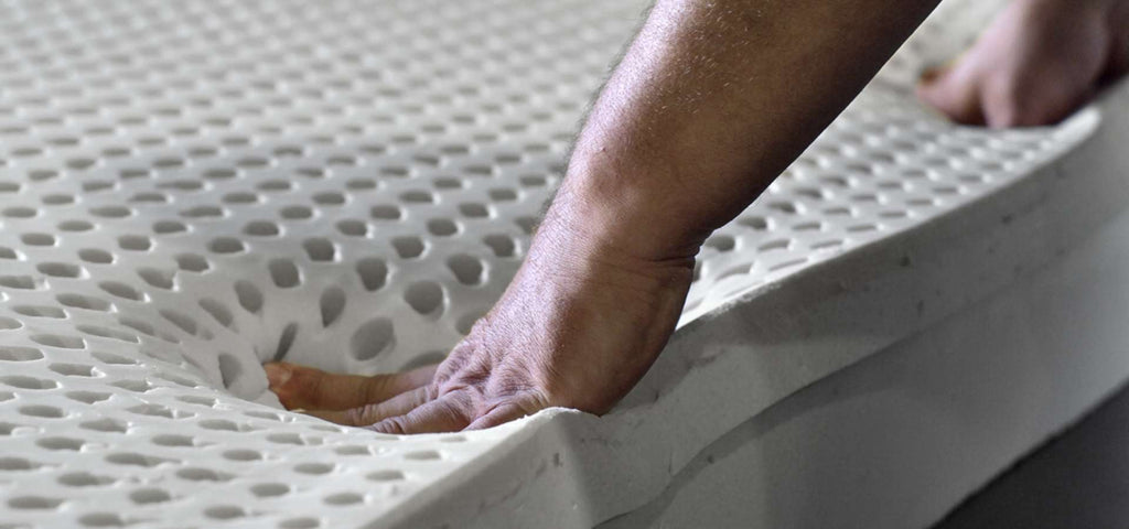 man pushing down on a slab of organic latex