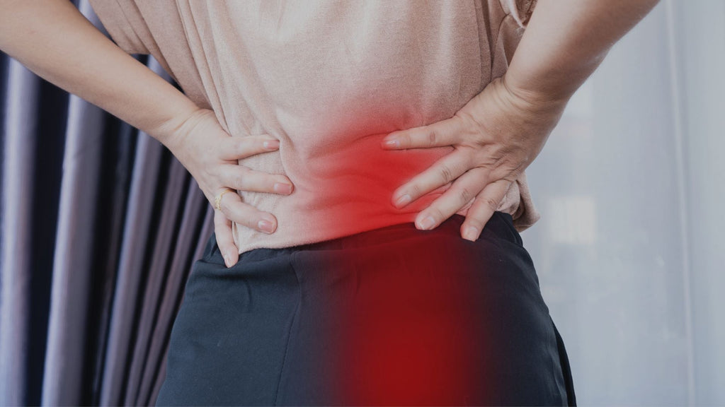 Woman holding her lower back while red area shows where sciatic pain travels