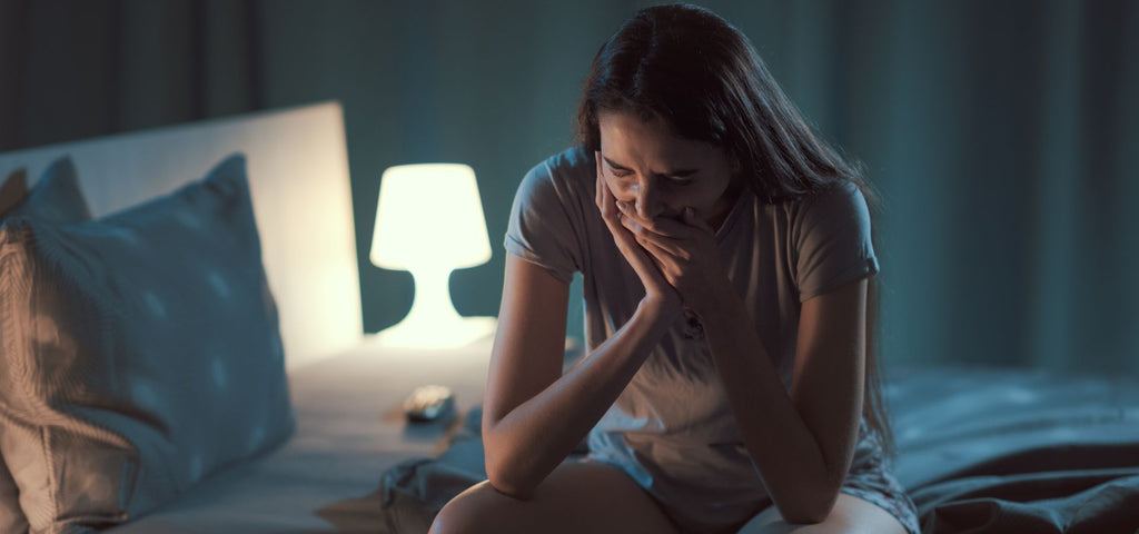 Woman sitting on the edge of her bed yawning