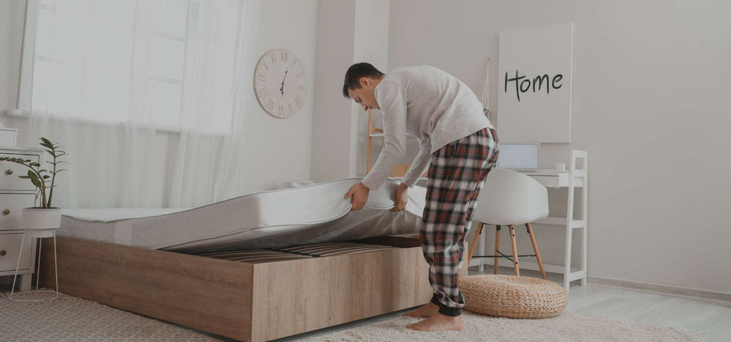 Man placing vegan mattress on his bed frame.