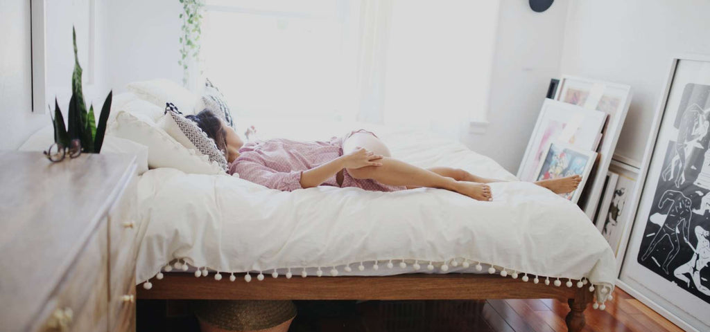 Woman wearing pink pjs and relaxing in her bed