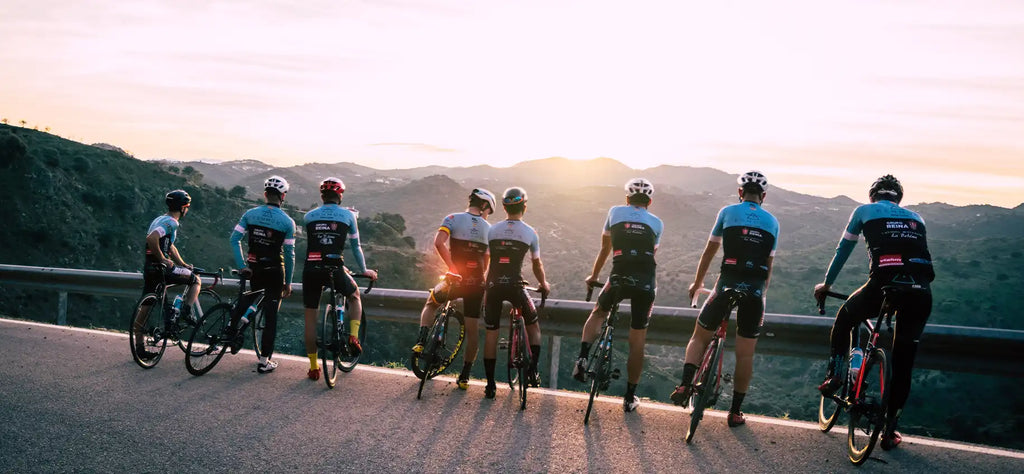 Cyclists admiring the sunset across a mountain range.