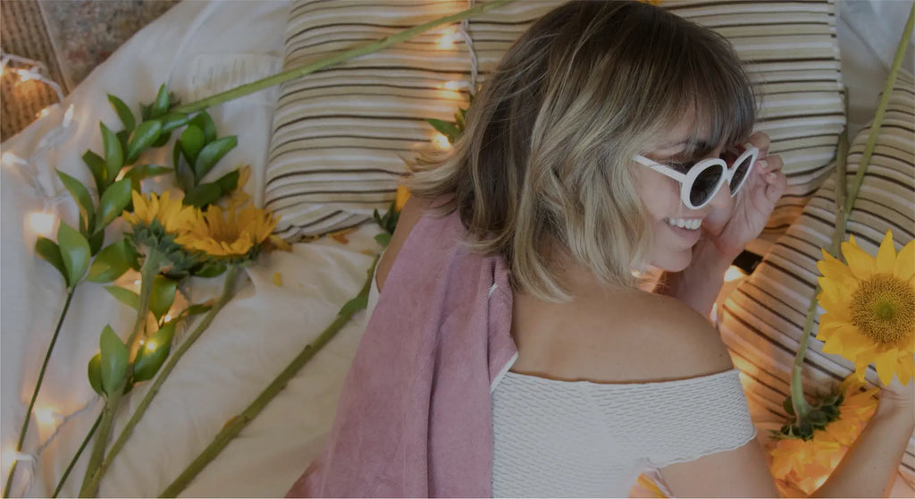 Essentia influencer wearing sunglasse on bed with flowers