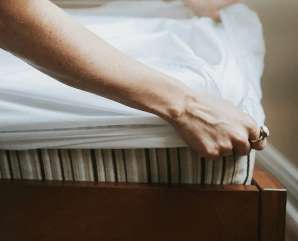 An arm reaching out to spread sheets to make the bed