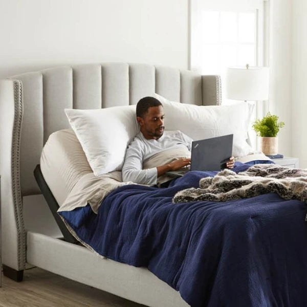 Man shown in an adjustable bed while using his laptop