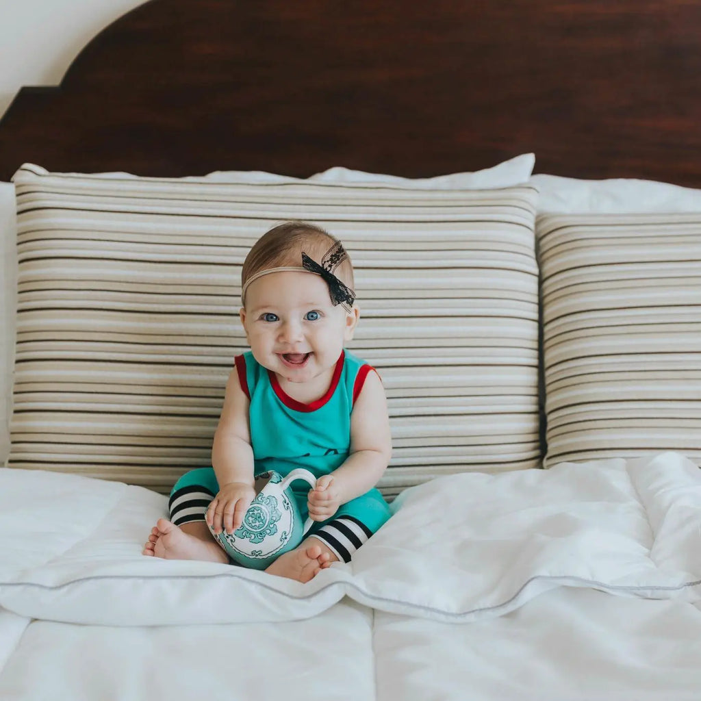 baby sitting on bed in front of Essentia Classic organic foam pillows