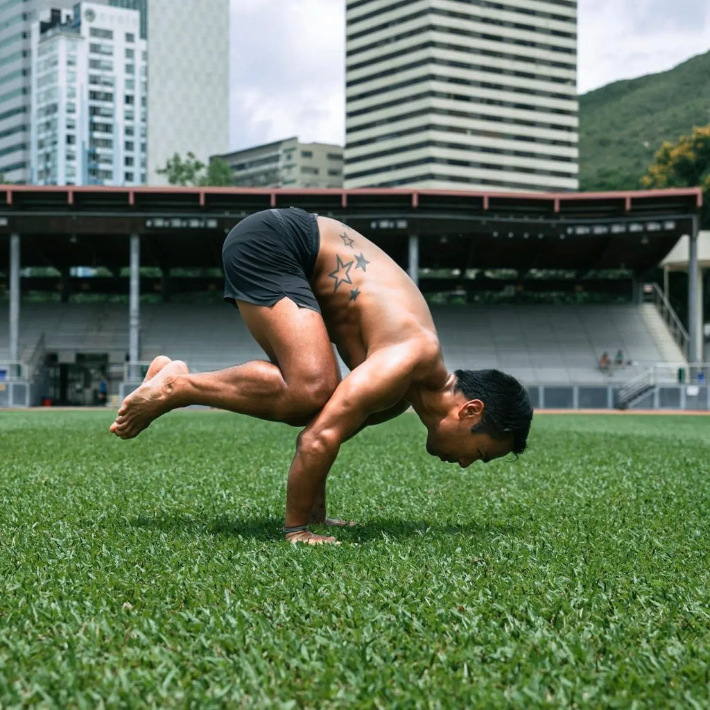 man practicing his yoga handstand outside in the grass