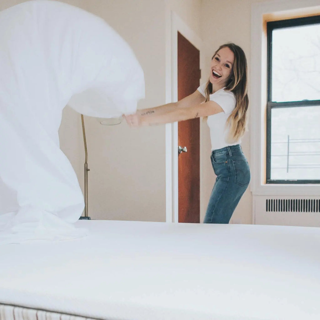 Woman putting Essentia GOTS certified organic cotton sheets on her mattress