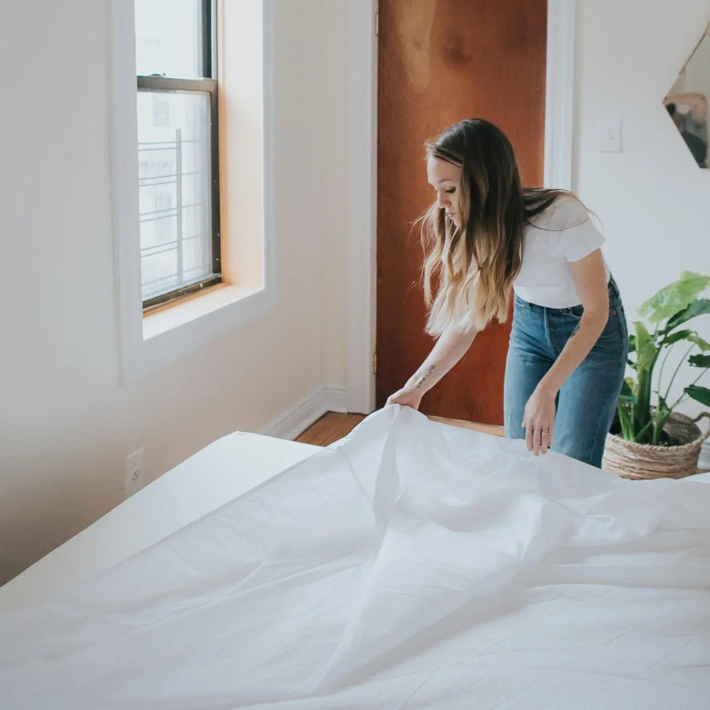 Woman putting Essentia GOTS certified organic cotton sheets on her mattress